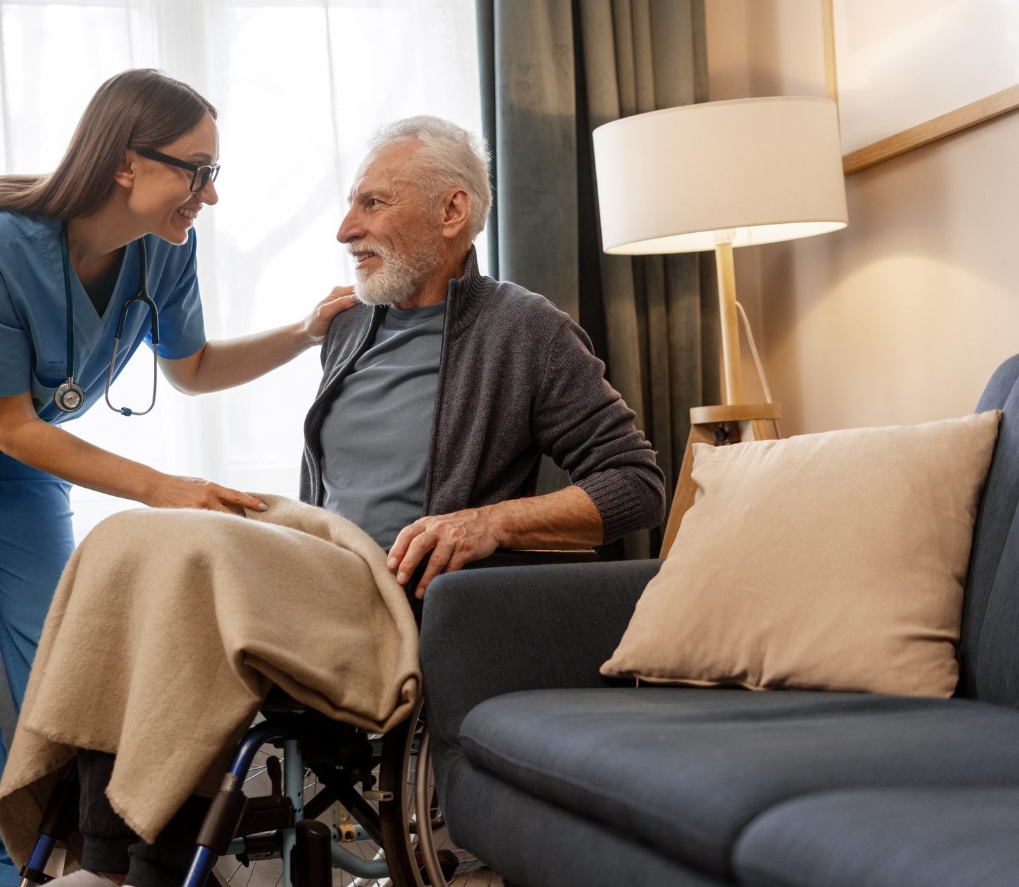 Pflegerin im vertrauten Gespräch mit einem Senior im Wohnzimmer